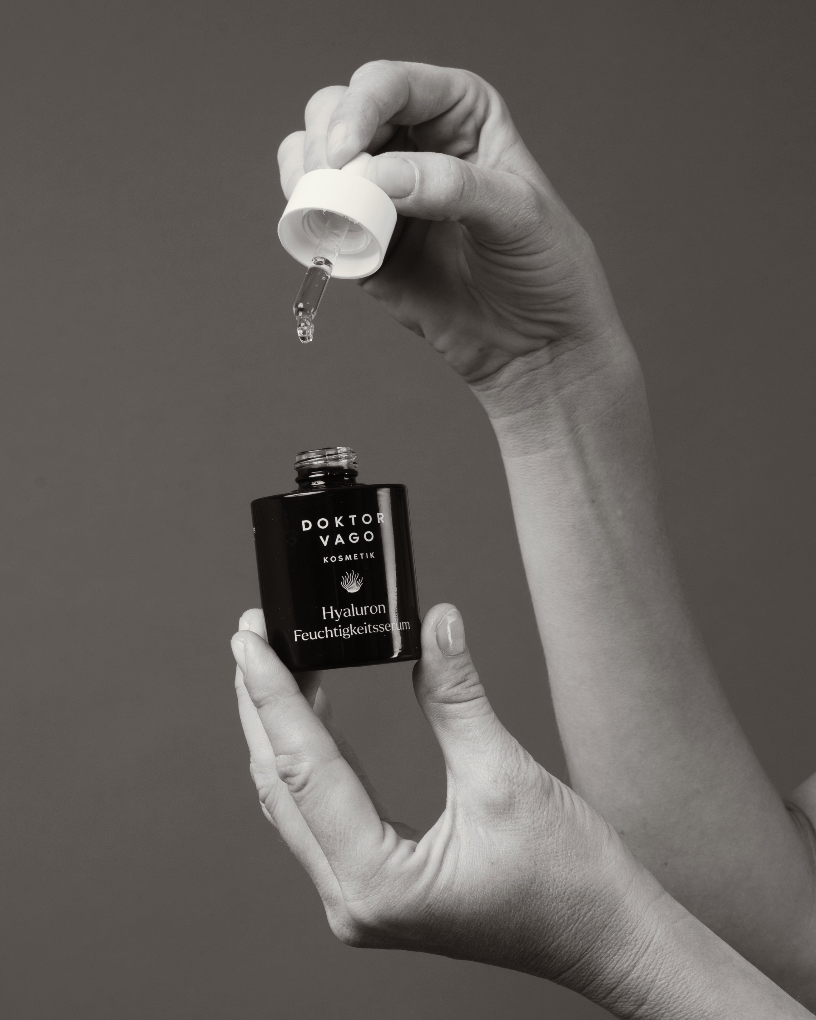Hände halten das Dr. Vago Hyaluron Feuchtigkeitsserum mit geöffnetem Dropper – Anwendung des Intensiv Hyaluron Serums mit Rotalgen-Zellwasser-Basis von Doktor Vago Kosmetik
